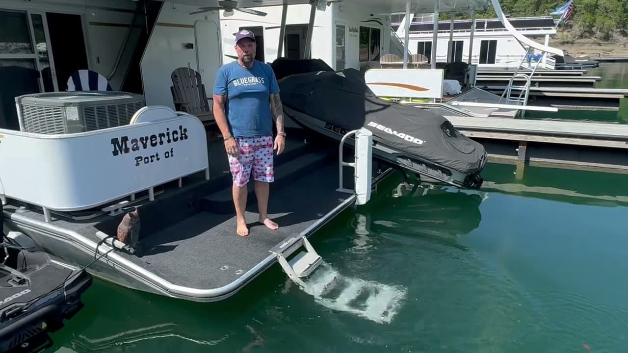 A renter on a houseboat swim deck unfolds the nautiDAWGS ladder, sets it into the guide clips and lowers it into the water